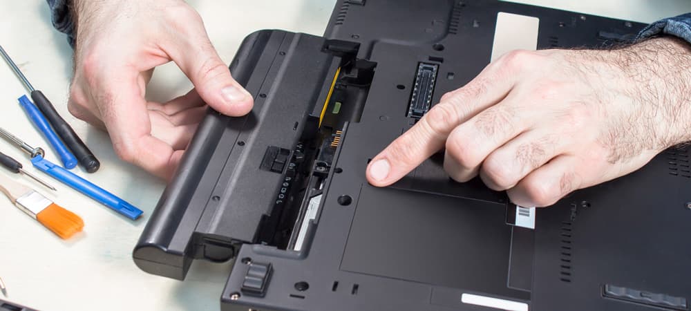 Laptop service. Removal of the battery by a service technician. Tools lie on the table. Laptop Battery Repair
